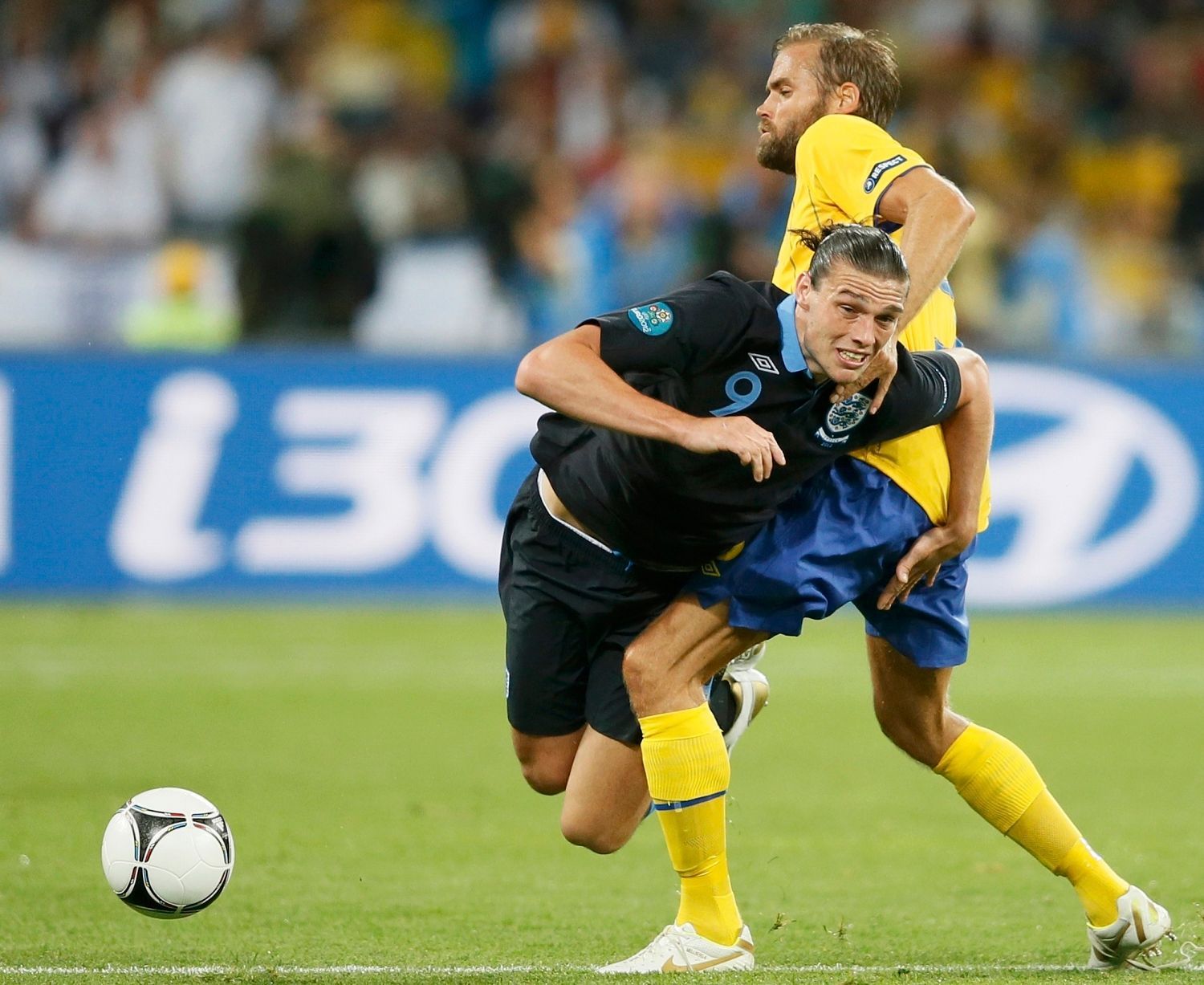 Anglický fotbalista Andy Carroll padá přes nohu Švéda Olofa Mellberga v utkání skupiny D na Euru 2012