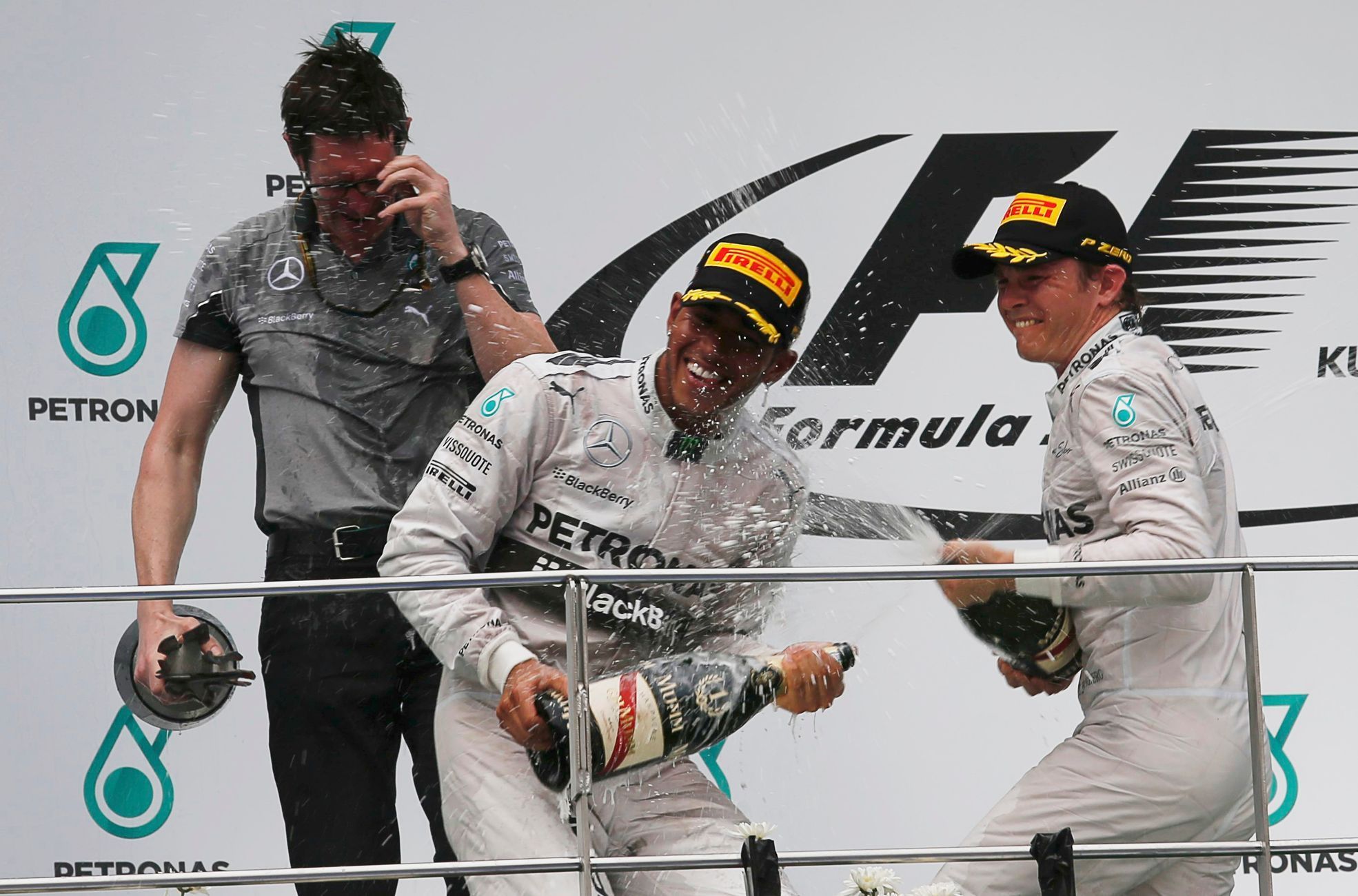 Mercedes Formula One driver Hamilton of Britain celebrates with team mate second-placed Rosberg of Germany and team engineer Shovlin after winning the Malaysian F1 Grand Prix at Sepang International C
