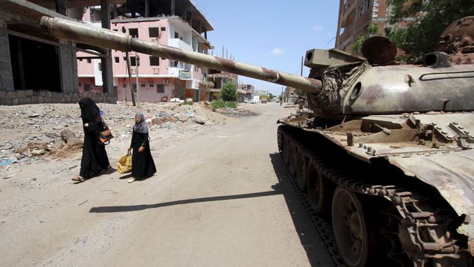 Ženy procházejí okolo rozbitého tanku v jemenském Adenu. Ilustrační foto.