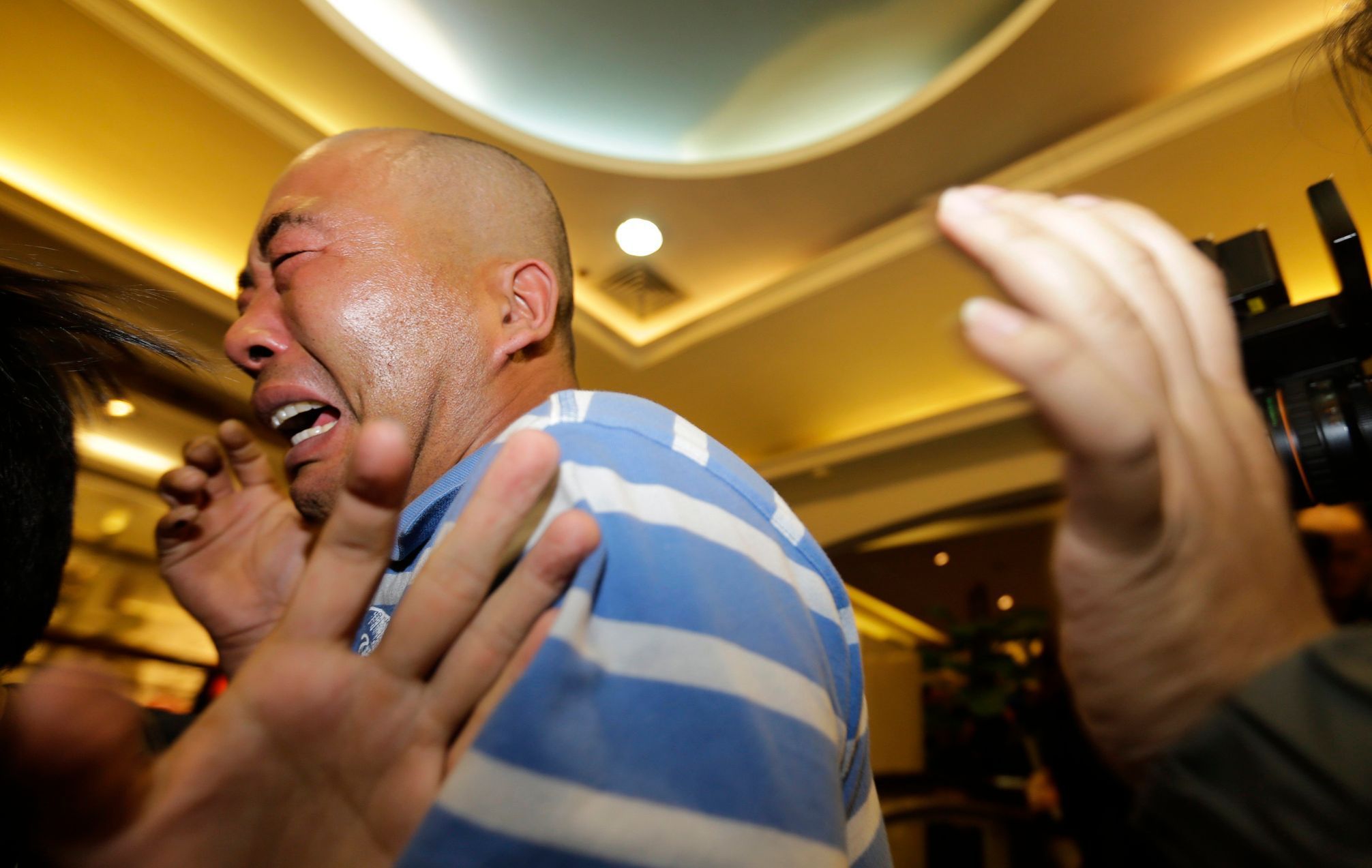 Relatives of passengers aboard Malaysia Airlines MH370 cry after watching a television broadcast of a news conference, in the Lido hotel in Beijing