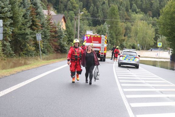 Hasič Miroslav Sedláček vede ženu za jejím manželem poté, co ji zachránil s dalšími hasiči před velkou vodou.