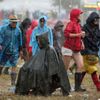 A man takes shelter from the rain in a poncho in front of the Other Stage at Worthy Farm in Somerset, during the Glastonbury Festival
