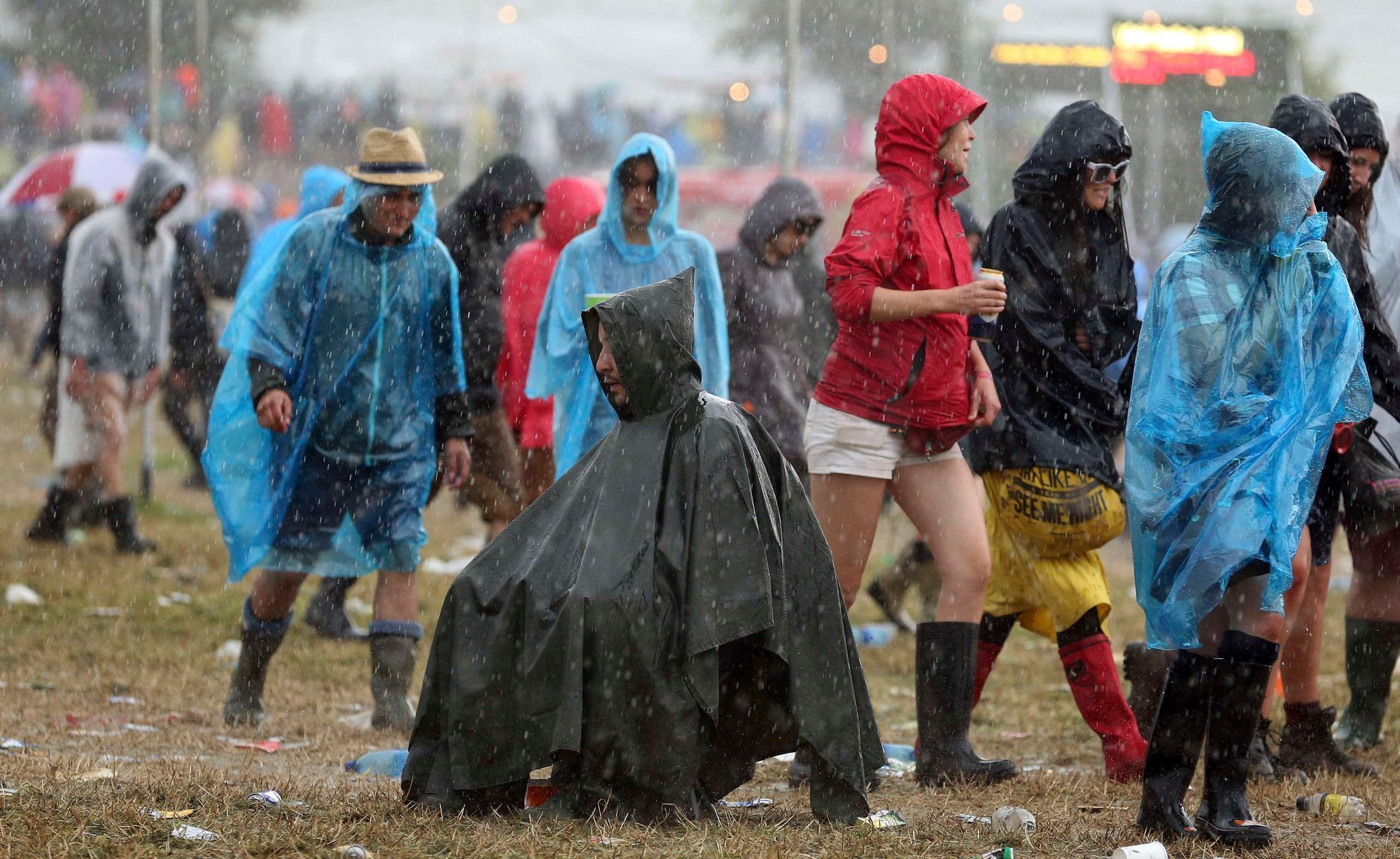 A man takes shelter from the rain in a poncho in front of the Other Stage at Worthy Farm in Somerset, during the Glastonbury Festival