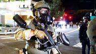 Federální důstojník policie sleduje pohyb protestujících před ústředím imigrační služby, připraven v případě potřeby zasáhnout.