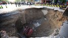 ¨Workers block off the site of a huge sinkhole which occured overnight in Shiliuzhuang road, in Beijing on April 26, 2011. A section of the road collapsed beneath a truck, slightly injuring the driver and a passenger, who both jumped out the vehicle beforeit sank into the hole, as an authoritiy suspects the hole was caused by the construction of a subway line. TOPSHOTS CHINA OUT AFP PHOTO