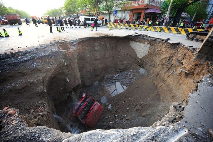 ¨Workers block off the site of a huge sinkhole which occured overnight in Shiliuzhuang road, in Beijing on April 26, 2011. A section of the road collapsed beneath a truck, slightly injuring the driver and a passenger, who both jumped out the vehicle beforeit sank into the hole, as an authoritiy suspects the hole was caused by the construction of a subway line. TOPSHOTS CHINA OUT AFP PHOTO