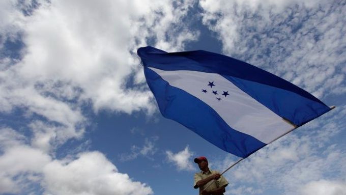 Stoupenec svrženého prezidenta mává honduraskou vlajkou, protestní akce pravidelně svolávají přívrženci obou táborů.