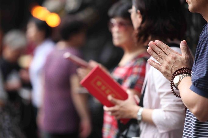 Při meditaci buddhisté odříkávají mantry na dřevěných korálcích.