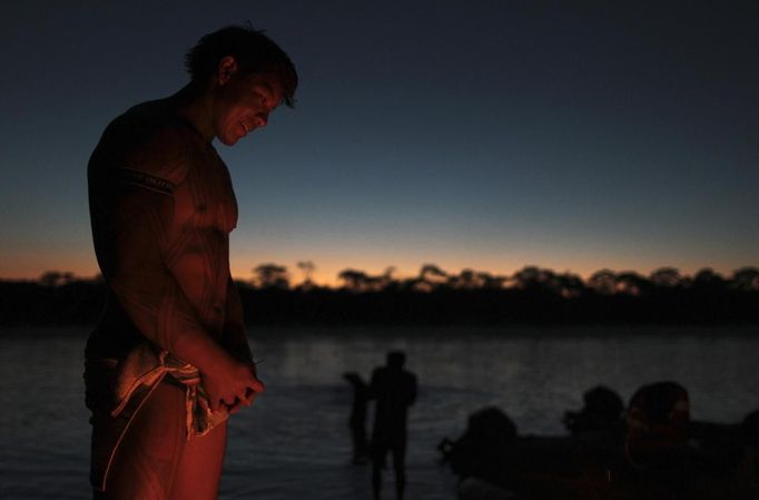 A Yawalapiti man warms himself over a fire after bathing in the Tuatuari River during this year's 'quarup,' a ritual held over several days to honour in death a person of great importance to them, in the Xingu National Park, Mato Grosso State, August 18, 2012. This year the Yawalapiti tribe honoured two people - a Yawalapiti Indian who they consider a great leader, and Darcy Ribeiro, a well-known author, anthropologist and politician known for focusing on the relationship between native peoples and education in Brazil. Picture taken August 18, 2012. REUTERS/Ueslei Marcelino (BRAZIL - Tags: SOCIETY ENVIRONMENT) FOR EDITORIAL USE ONLY. NOT FOR SALE FOR MARKETING OR ADVERTISING CAMPAIGNS. ATTENTION EDITORS - PICTURE 36 OF 37 FOR THE PACKAGE 'THE YAWALAPITI QUARUP RITUAL' Published: Srp. 29, 2012, 10:21 dop.