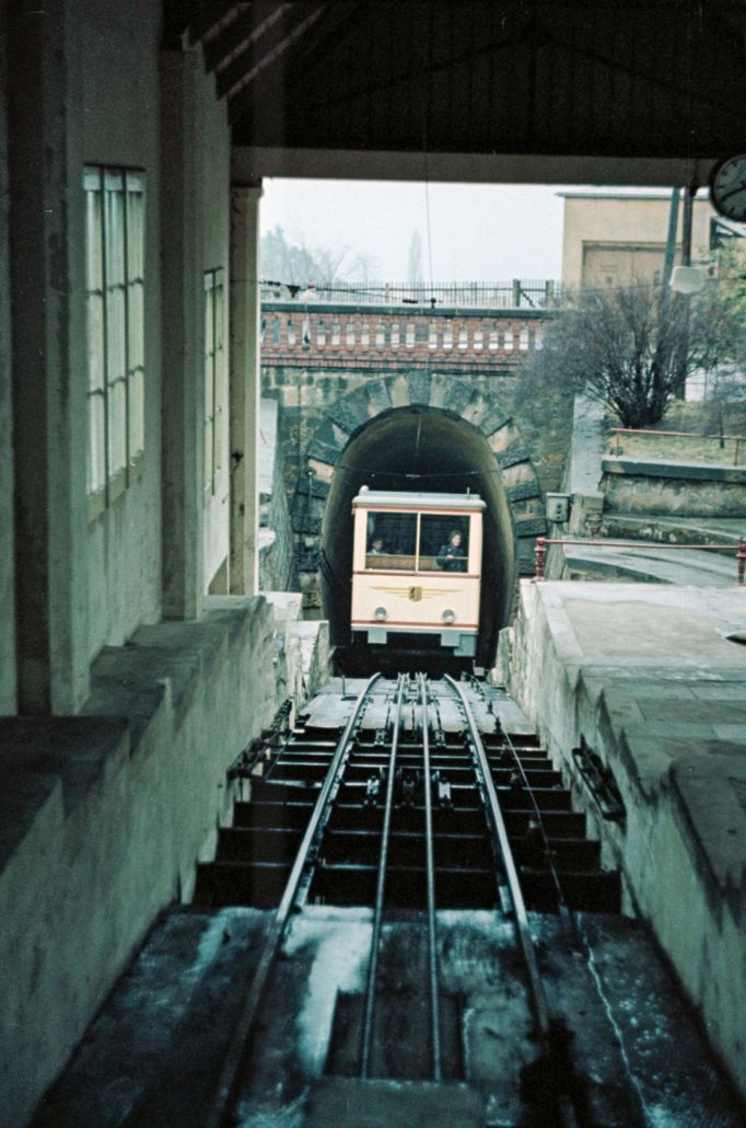 Historická fotografie zachycuje horní stanici lanovky (Standseilbahn) v drážďanské čtvrti Weisser Hirsch v roce 1957. Vůz lanovky vjíždí do tunelu na konci trati.