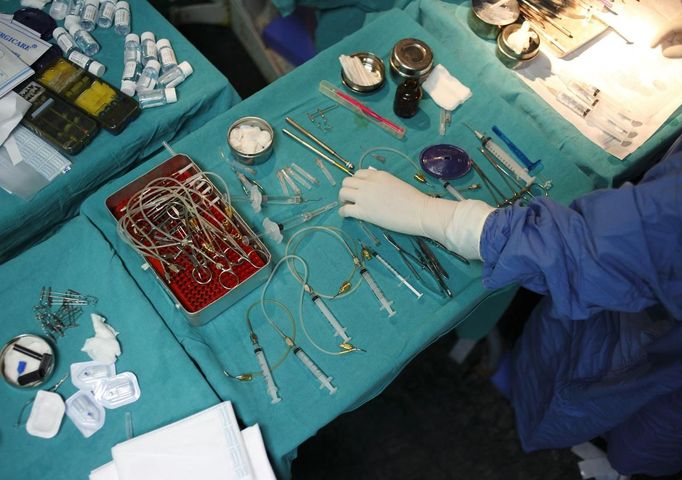 A nurse passes equipments laid out on a table to a surgeon during a cataract surgery at the Tilganga Eye Center in Kathmandu April 25, 2012. About 150,000 of Nepal's 26.6 million people are estimated to be blind in both eyes, most of them with cataracts. Picture taken April 25, 2012. REUTERS/Navesh Chitrakar (NEPAL - Tags: HEALTH SOCIETY POVERTY) Published: Kvě. 2, 2012, 5:09 dop.