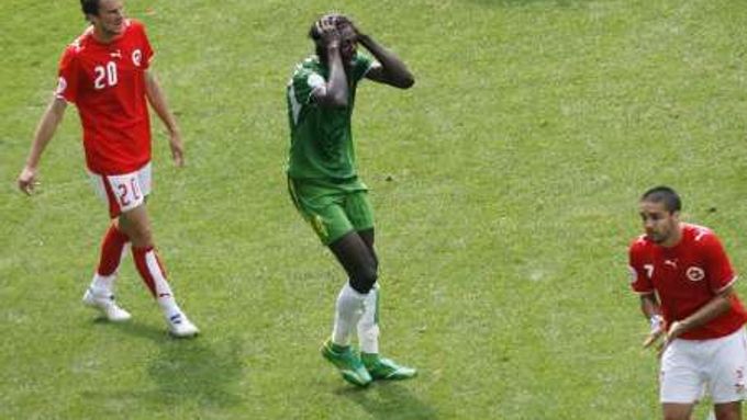 Emmanuel Adebayor z Toga (v zeleném) se drží za halvu poté, co nebyl odpískán faul Švýcara Patricka Müllera na něj v pokutovém území.