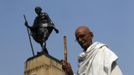 Mahesh Chaturvedi, 63, who dresses up like Mahatma Gandhi, poses for a photo in front of a statue of Gandhi in the old quarters of New Delhi October 25, 2012. Chaturvedi says that the soul of Gandhi resides in him and he has been sent to continue the work of Father of the Nation. After his self proclaimed transformation in 2002 as Gandhi, Chaturvedi has been travelling extensively and plays up to his startling resemblance to Gandhi at protests and demonstrations. Picture taken October 25, 2012. REUTERS/Mansi Thapliyal (INDIA - Tags: SOCIETY) Published: Lis. 26, 2012, 4 dop.