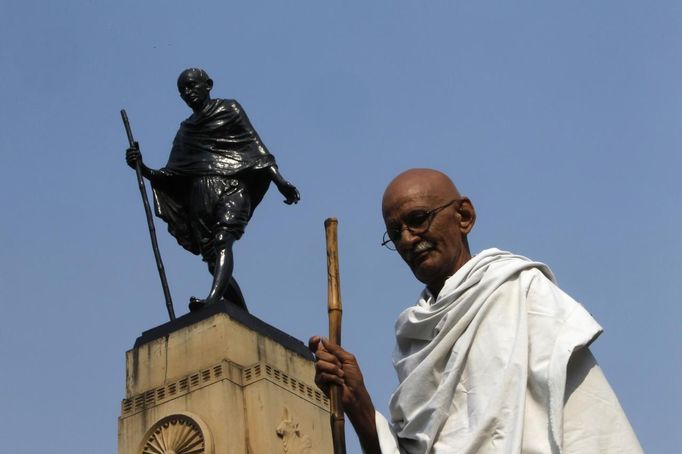 Mahesh Chaturvedi, 63, who dresses up like Mahatma Gandhi, poses for a photo in front of a statue of Gandhi in the old quarters of New Delhi October 25, 2012. Chaturvedi says that the soul of Gandhi resides in him and he has been sent to continue the work of Father of the Nation. After his self proclaimed transformation in 2002 as Gandhi, Chaturvedi has been travelling extensively and plays up to his startling resemblance to Gandhi at protests and demonstrations. Picture taken October 25, 2012. REUTERS/Mansi Thapliyal (INDIA - Tags: SOCIETY) Published: Lis. 26, 2012, 4 dop.