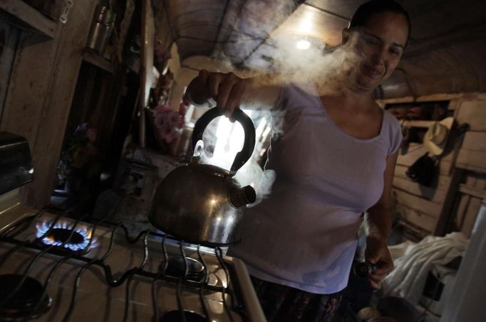 Maria de los Santos boils water for coffee inside a train carriage she calls home in Cadereyta on the outskirts of Monterrey August 8, 2012. Maria de los Santos, her eight other family members and their pets have been living in the abandoned carriage next to a train track for the last 15 years. Maria de los Santos parents moved from Tamaulipas to Cadereyta after one of their sons was killed on the street by a stray bullet. The family moved into the carriage, which was empty after having been occupied by a vagabond, after living for the first five years in a rented room after arriving in Cadereyta. Picture taken August 8, 2012. REUTERS/Daniel Becerril (MEXICO - Tags: SOCIETY) Published: Srp. 11, 2012, 1:55 dop.