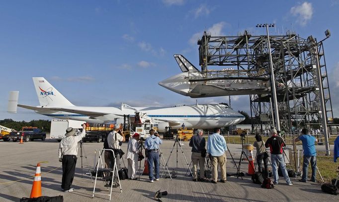 Photographers look on as space shuttle Discovery is approached by a NASA 747 aircraft being towed towed into the Mate Demate facility at Kennedy Space Center in Cape Canaveral