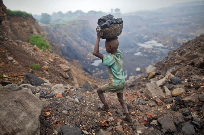 A boy carries coal at an open cast coal field at Dhanbad district in the eastern Indian state of Jharkhand September 20, 2012. With oil and gas output disappointing and hydropower at full throttle, Asia's third-largest economy still relies on coal for most of its vast energy needs. About 75 percent of India's coal demand is met by domestic production and, according to government plans, that won't change over the next five years. Picture taken September 20, 2012. To match INDIA-COAL/ REUTERS/Ahmad Masood (INDIA - Tags: BUSINESS EMPLOYMENT ENERGY SOCIETY ENVIRONMENT) Published: Říj. 21, 2012, 10:22 odp.