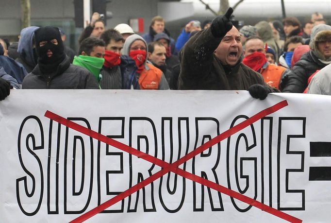 Arcelor Mittal workers from the Liege site hold a banner during a demonstration outside Prime Minister Elio Di Rupo's office where a political meeting is taking place, in Brussels January 25, 2013. ArcelorMittal the world's largest steel producer, plans to shut a coke plant and six fininishing lines at its site in Liege Belgium, affecting 1,300 employees, the group said on Thursday. The word on the banner says, "Steel industry". REUTERS/Yves Herman (BELGIUM - Tags: BUSINESS CIVIL UNREST EMPLOYMENT) Published: Led. 25, 2013, 12:14 odp.