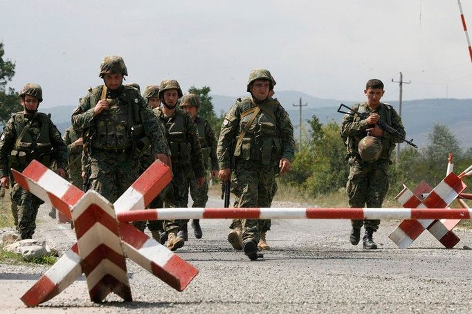 Gruzínští vojáci přecházejí skrz zátarasy opuštěného stanoviště ruských mírových jednotek v Jižní Osetii.