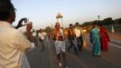 A man takes a photo as Mahesh Chaturvedi (C), 63, who dresses up like Mahatma Gandhi, walks near the India Gate in New Delhi October 4, 2012. Chaturvedi says that the soul of Gandhi resides in him and he has been sent to continue the work of Father of the Nation. After his self proclaimed transformation in 2002 as Gandhi, Chaturvedi has been travelling extensively and plays up to his startling resemblance to Gandhi at protests and demonstrations. Picture taken October 4, 2012. REUTERS/Mansi Thapliyal (INDIA - Tags: SOCIETY) Published: Lis. 26, 2012, 4 dop.