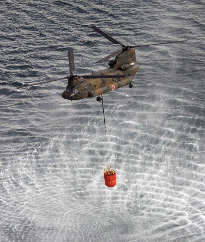 Armádní helikoptéra Chinook CH-47 nabírá vodu z oceánu a společně s kyselinou boritou jí bude kropit požár v jaderné elektrárně Fukušima.