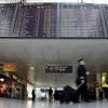 Pilots pass flight schedule board announcing cancelled flights by German air carrier Lufthansa at Munich's airport