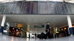 Pilots pass flight schedule board announcing cancelled flights by German air carrier Lufthansa at Munich's airport