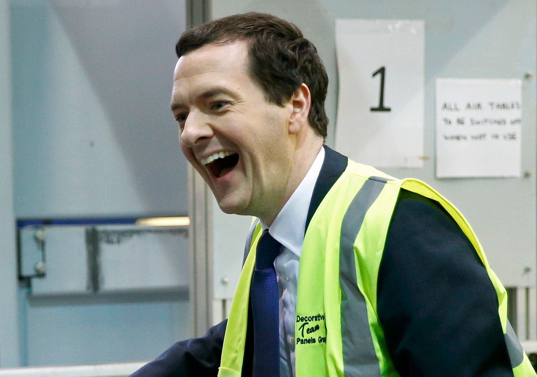 Britain's Chancellor of the Exchequer George Osborne laughs as he works on a production line of decorative panels at a factory in Stockton-on-Tees