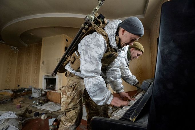 Vojáci ukrajinské armády hrají na piano ve zničeném domě poblíž frontové linie na Donbasu, kde bojují s proruskými separatisty.