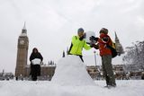 Rodina staví sněhuláka na prostranství před britským parlamentem.