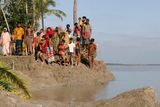 Lidé, kteří přečkali řádění cyklonu, postávají na zhrouceném břehu řeky Paira a čekají na záchranáře.