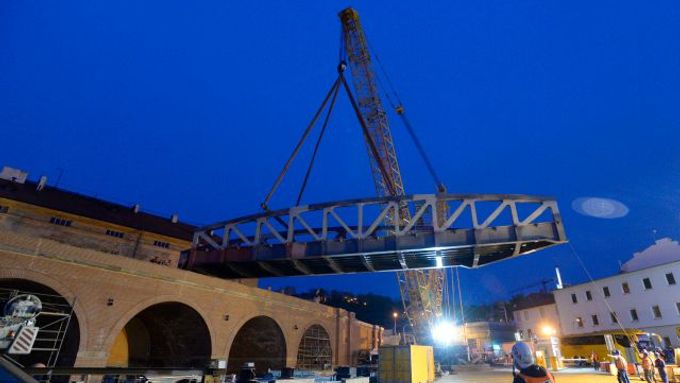 Obří jeřáb nasazuje most na Negrelliho viadukt.