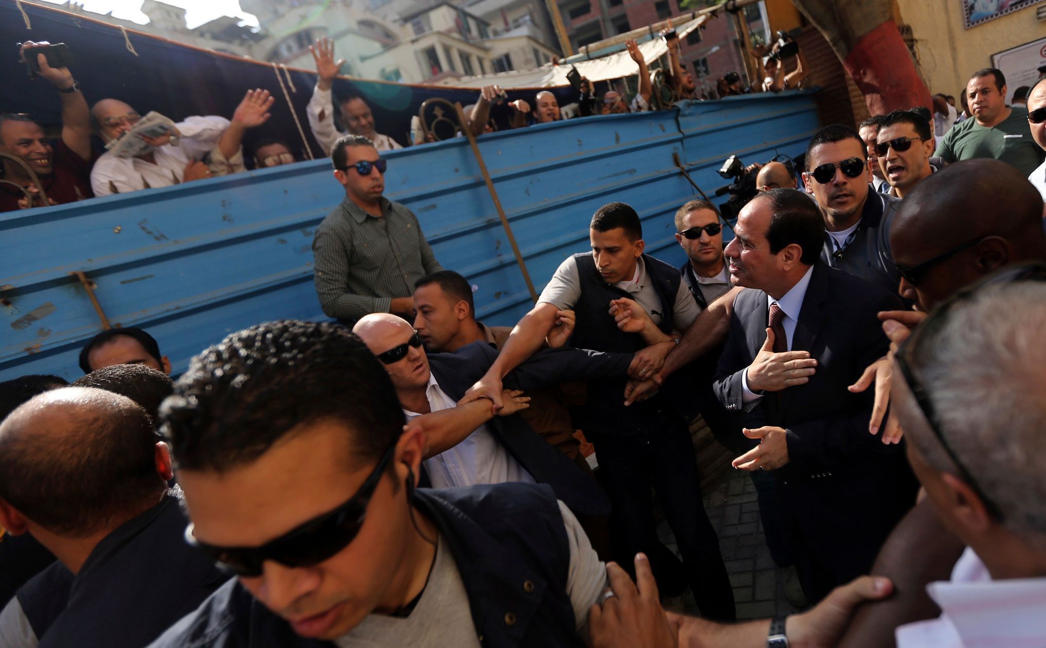 Sísí v kravatě zdraví lidi před volební místností v Káhiře.