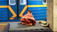 Dívka se schovává pod dekou, její jediný úkryt před válečnou vřavou během poplachu v kyjevském metru.