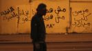 A protester, who opposes Egyptian President Mohamed Mursi, walks during clashes with riot police in front of the presidential palace in Cairo February 11, 2013. Protesters demanding the departure of Egyptian President Mohamed Mursi clashed with police outside his palace on Monday on the second anniversary of the overthrow of veteran autocrat Hosni Mubarak. The graffiti reads, "Police are thugs , Mursi dog of Mubarak." REUTERS/Amr Abdallah Dalsh (EGYPT - Tags: POLITICS CIVIL UNREST) Published: Úno. 11, 2013, 11:59 odp.