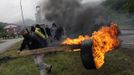 A coal miner uses a plank to carry a burning tire to be used as a barricade in front of the main gate of the "Pozo Santiago" mine in Caborana, near Oviedo, northern Spain June 18, 2012. Spanish coal mining unions are taking part in a general strike in northern Spain mining areas to protest against government action to cut coal subsidies. REUTERS/Eloy Alonso (SPAIN - Tags: CIVIL UNREST BUSINESS EMPLOYMENT ENERGY TPX IMAGES OF THE DAY) Published: Čer. 18, 2012, 1:04 odp.