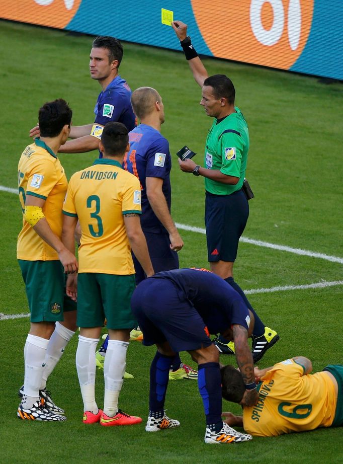 Australia's Matthew Spiranovic (R) lies on the pitch after being fouled by Robin van Persie (top L) of the Netherlands, who is shown the yellow card by referee Djamel Hai