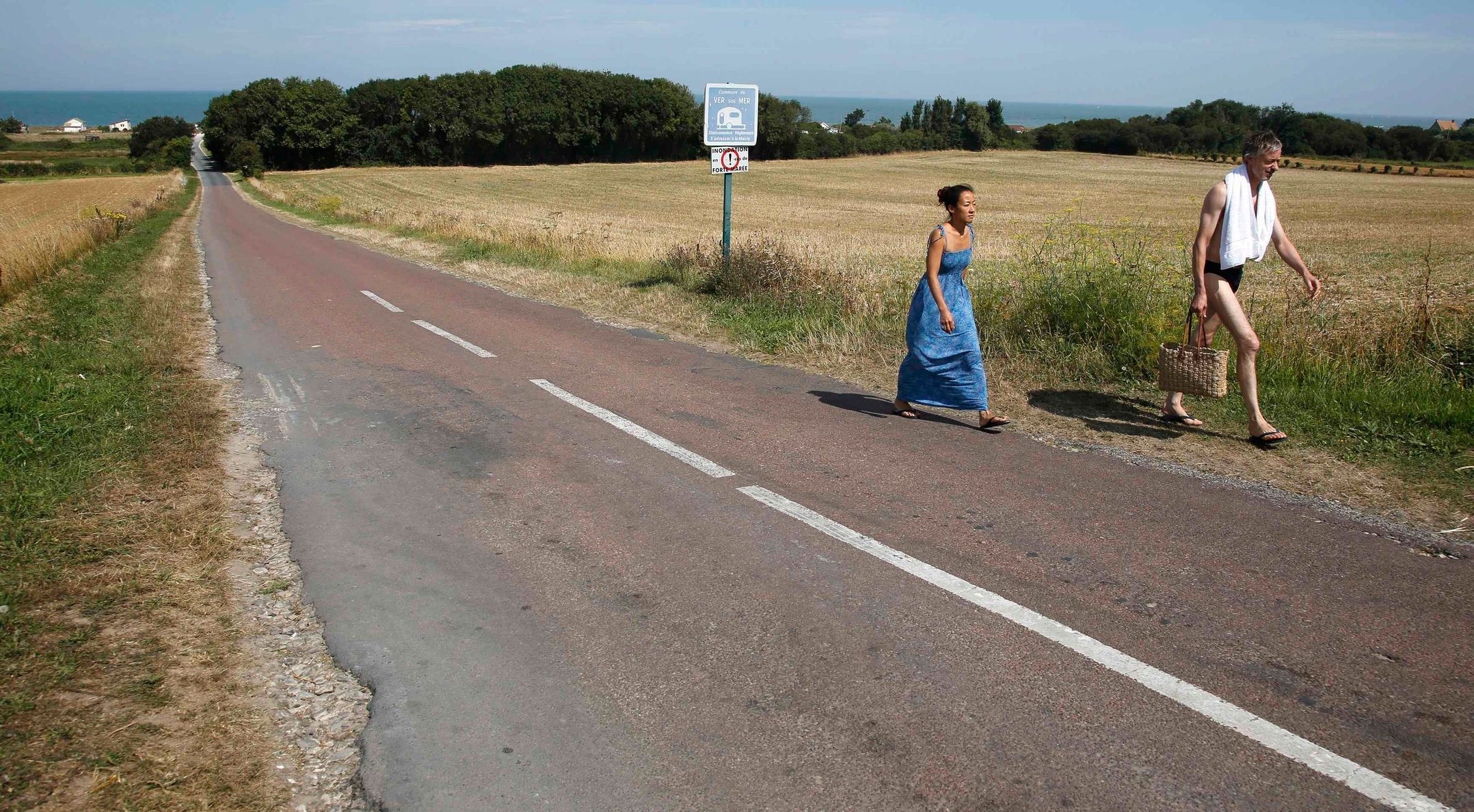 A couple walk inland from the former D-Day landing zone of Gold Beach in Ver-sur-Mer