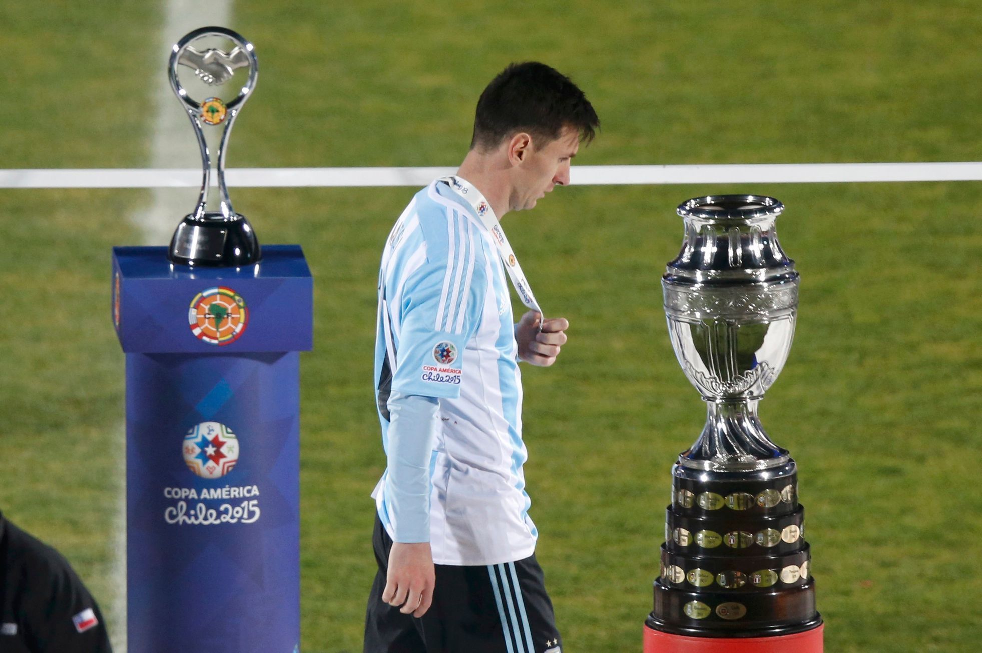 Argentina's Lionel Messi walks with his silver medal past the Copa America trophy during the presentation ceremony after Chile defeated his team in the Copa America 2015 final soccer match at the Nati