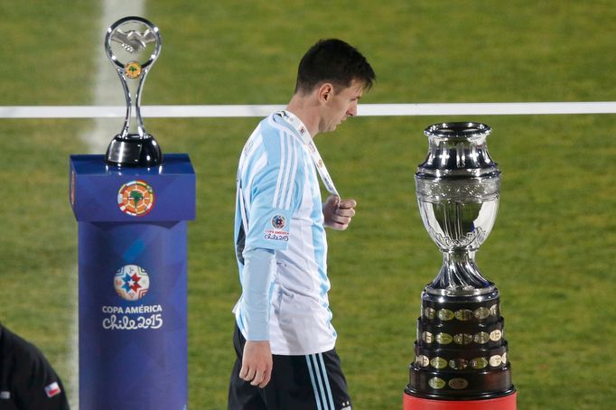 Argentina's Lionel Messi walks with his silver medal past the Copa America trophy during the presentation ceremony after Chile defeated his team in the Copa America 2015