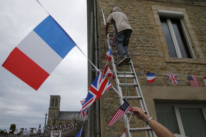 Local residents hang up flags during preparations for the 75th anniversary of the D-Day Normandy landings, in La Cambe, France, June 4, 2019. REUTERS/Pascal Rossignol