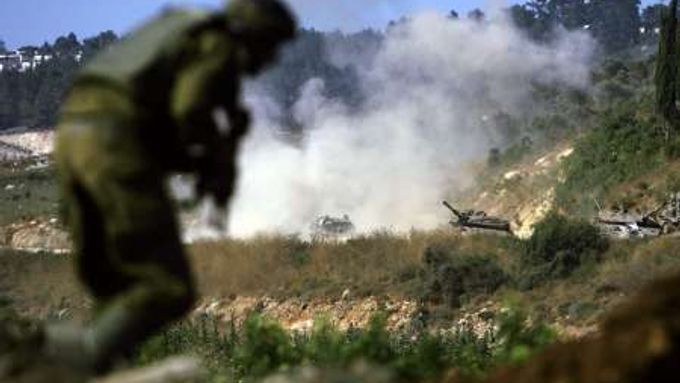 Izraelský voják prchá do úkrytu - dál od tanku, který dostal poblíž libanonské hranice zásah.
