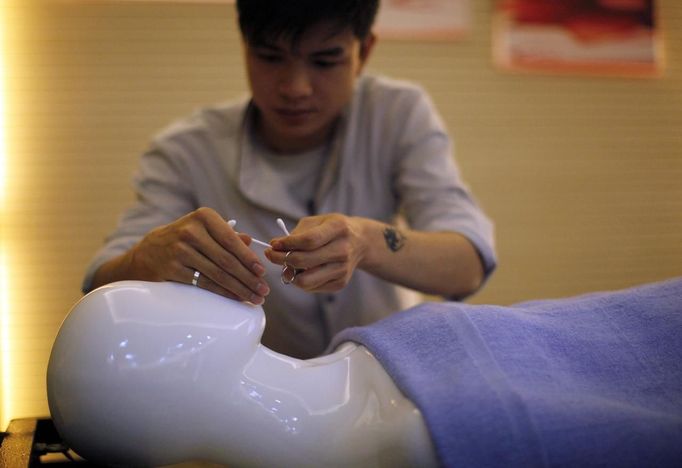 A student practices with a mannequin during their undertaker service class at the Tianquanjiajing Funeral Service school in Jiaxing, Zhejiang province May 29, 2012. A new breed of young Chinese undertakers are fighting centuries-old taboos to gain social acceptance for their profession, saying they help the deceased and their families make their final parting with respect. There are more than 1,500 students across the country studying to become undertakers each year. Courses in funeral services take three years to complete and the service includes washing of the dead body as well as providing funeral make-up and dressing. Picture taken May 29, 2012. REUTERS/Carlos Barria (CHINA - Tags: SOCIETY) ATTENTION EDITORS - PICTURE 14 OF 17 FOR PACKAGE 'FUNERAL SERVICE STUDENTS' Published: Čer. 7, 2012, 2:44 dop.