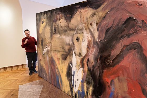 Tibor Červeňák instaluje na výstavě v Oblastním muzeu a galerii v Mostě svůj obraz Wild horses from Brecon Beacons (Divocí koně z Brecon Beacons).