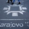People walk past the logo of the Winter Olympics in Sarajevo, painted on the streets in central Sarajevo