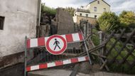 "Dlouho jsme neměli ani elektřinu a telefon, teď už zase ano. Jenže vedení pod povrchem vozovky jsou narušená. Než je přijdou zkontrolovat, tak tu těžko budeme něco obnovovat. Můj švagr nemůže znovu postavit zeď, kterou měl u domu," ukazuje směrem vzhůru do kopce Gottschild.