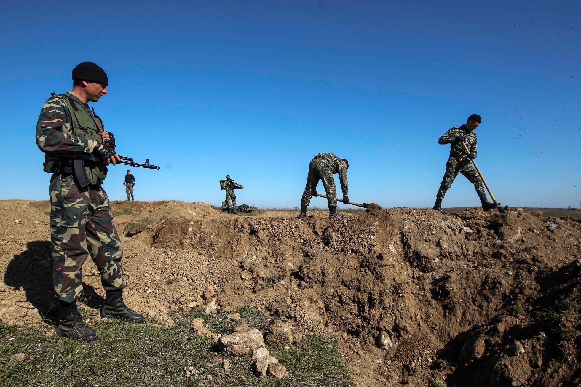 Ukrainian servicemen dig trenches at a checkpoint near the town of Armyansk