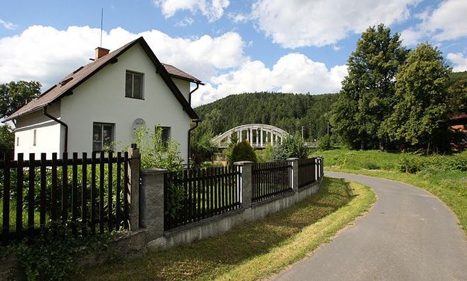 Tento obytný dům leží přímo v obci Nové Heřminovy, relativně daleko od plánované hráze. Přesto se ho stavba přehrady může také dotknout - od hráze totiž povede široké koryto. Řada místních pořád neví, kudy přesně. Most (vzadu) se bude muset určitě strhnout.