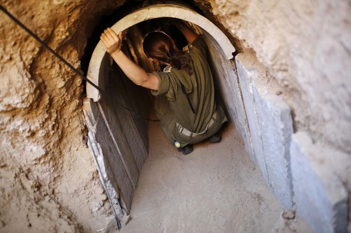 An Israeli soldier squats in a tunnel exposed by the Israeli military, just outside the southern Gaza Strip