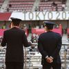 Členové bezpečnostní služby na okruhu ve Fudži sledují dojezd hromadného závodu mužů na OH 2020